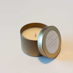 Lumânare parfumată Veraroma, model Velur la 90g deschisă, cu capacul sprijinit de cutia metalică aurie. Arome de bujor întunecat, oud afumat și ambră.